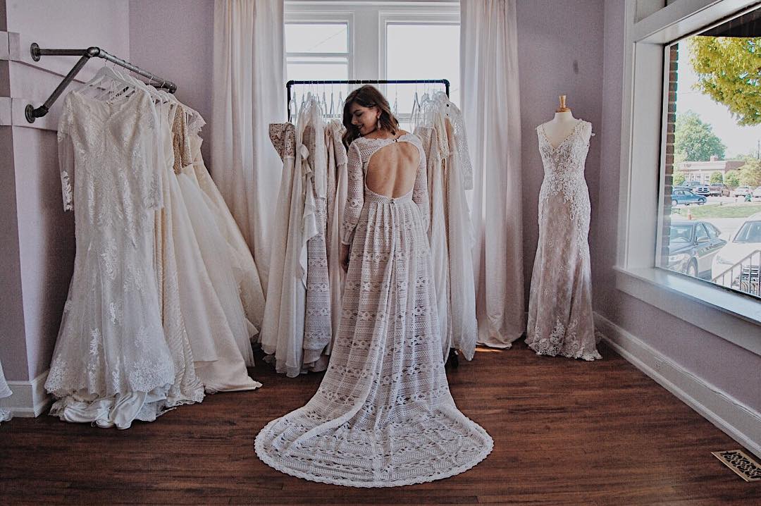 Model trying on a long-sleeved wedding dress with open back