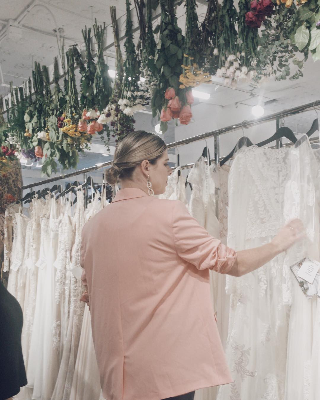 Blonde woman browsing through wedding dresses at Laced With Grace Bridal
